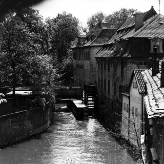 Historic European town with waterwheel and canal.