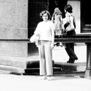 Woman standing beside equestrian statue in city plaza.