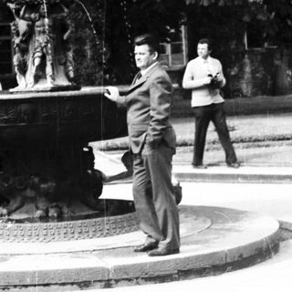 People gathered around ornate fountain in park.