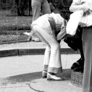 People posing near ornate fountain in park.