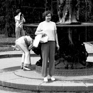 People posing near ornate fountain in park.