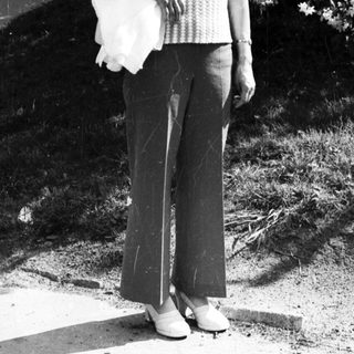 Woman smiling outdoors holding shopping bag.