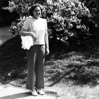 Woman smiling outdoors holding shopping bag.