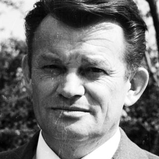 Portrait of a man in formal attire outdoors.