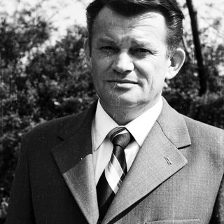 Portrait of a man in formal attire outdoors.