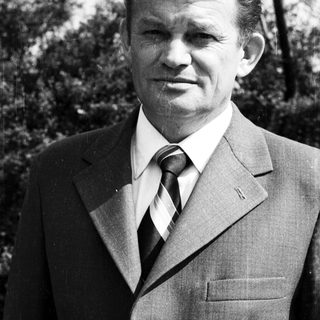 Portrait of a man in formal attire outdoors.