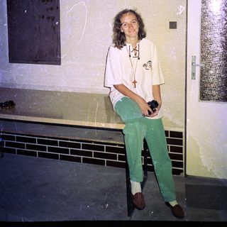 Person wearing medical scrubs holding camera indoors.