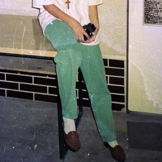Person wearing medical scrubs holding camera indoors.