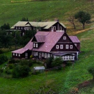 Rural countryside with houses on green hills.