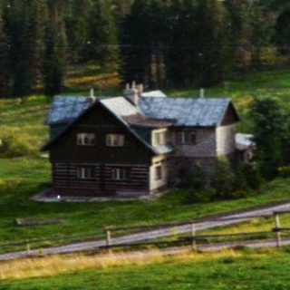 Rural countryside scene with houses, horse, winding road, and forested hills.