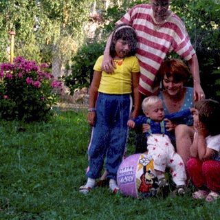 Family posing outdoors with children and dog.