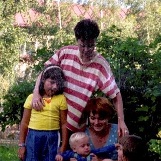 Family posing outdoors with children and dog.