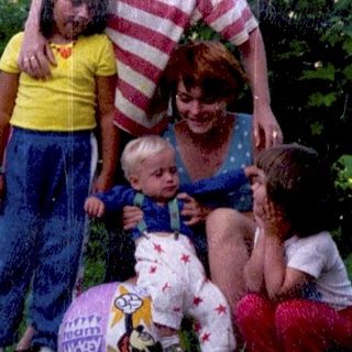 Family posing outdoors with children and dog.