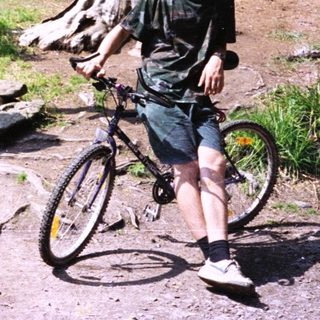 Young man posing with mountain bike near trail map.