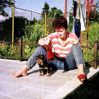 Person sitting with small dog outdoors.