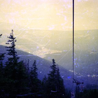 Mountainous landscape with fog and ski lift cables.