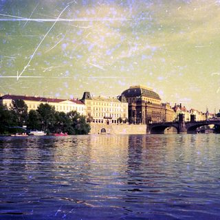 Historic European cityscape with river, bridges, and grand architecture.