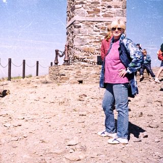 Two people hiking near a stone tower.