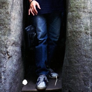 Two men standing in narrow, ancient stone corridor.