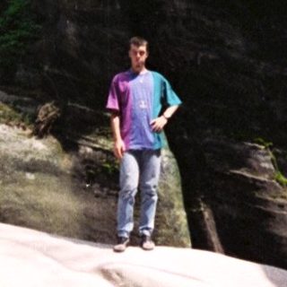 Person standing on large rock formations in forest.