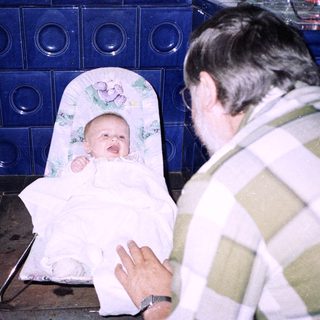 Baby being held and bathed by adult.