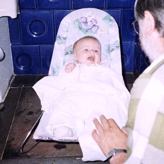 Baby being held and bathed by adult.