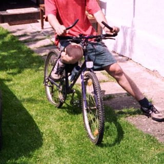 Man on bike near parked car.
