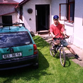 Man on bike near parked car.