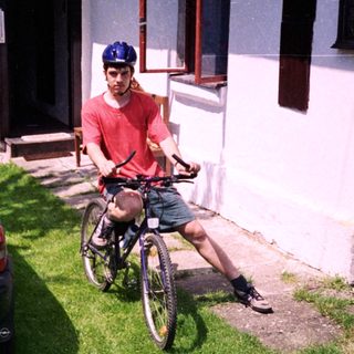 Man on bike near parked car.