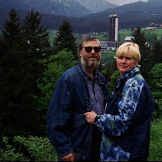 Two people standing on a scenic mountain road.