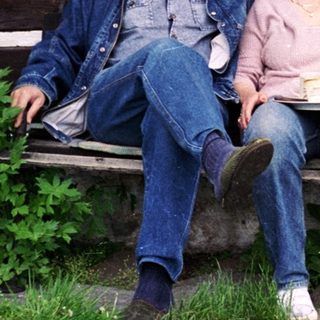Two people sitting on bench outside rustic wooden house with pets.