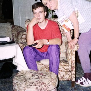 Two people indoors, one leaning on cane.