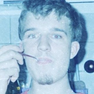 Young man eating while brushing teeth in kitchen.