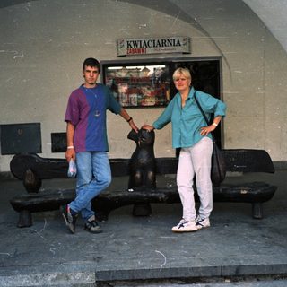 Two people posing near flower shop entrance.