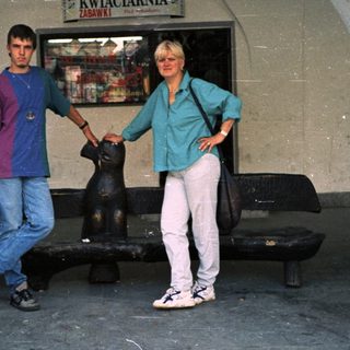 Two people posing near flower shop entrance.
