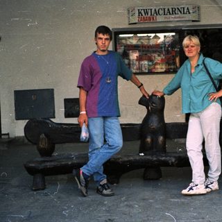 Two people posing near flower shop entrance.