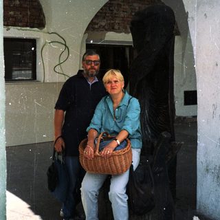 Two people posing together under an arched doorway holding a basket.
