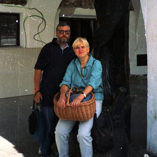 Two people posing together under an arched doorway holding a basket.