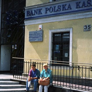 Two people sitting outside Bank Polska Kasprowicz.