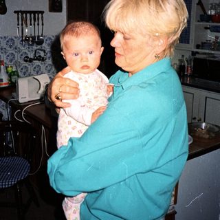 A woman holds a baby in a kitchen.