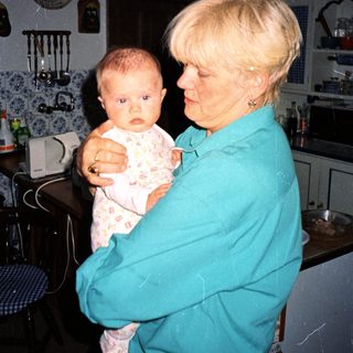 A woman holds a baby in a kitchen.