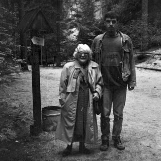 Two people hiking in a forested mountainous area.