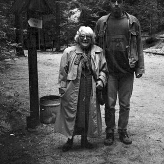 Two people hiking in a forested mountainous area.