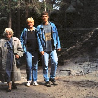 Three people walking together in a forested area.
