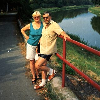 Happy couple posing by scenic river path.