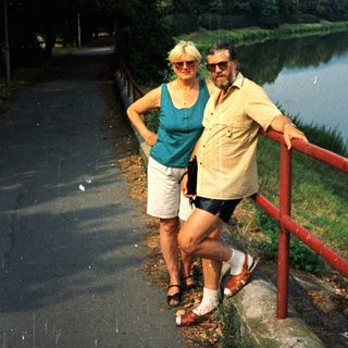 Happy couple posing by scenic river path.