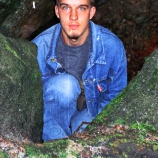 Person peeking from narrow cave entrance.