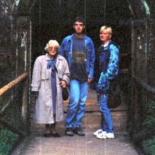 Three people standing on a wooden bridge inside a cave.