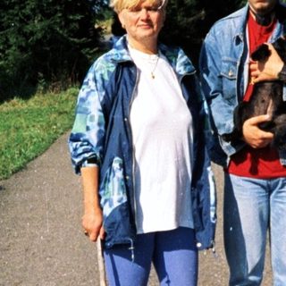 Three people hiking with a dog in a forested area.
