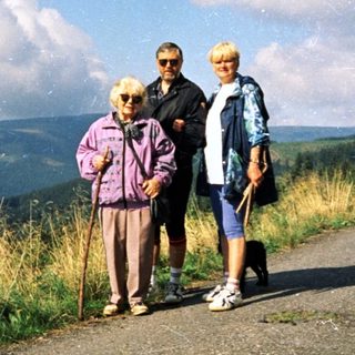 Three people hiking on scenic mountain road.